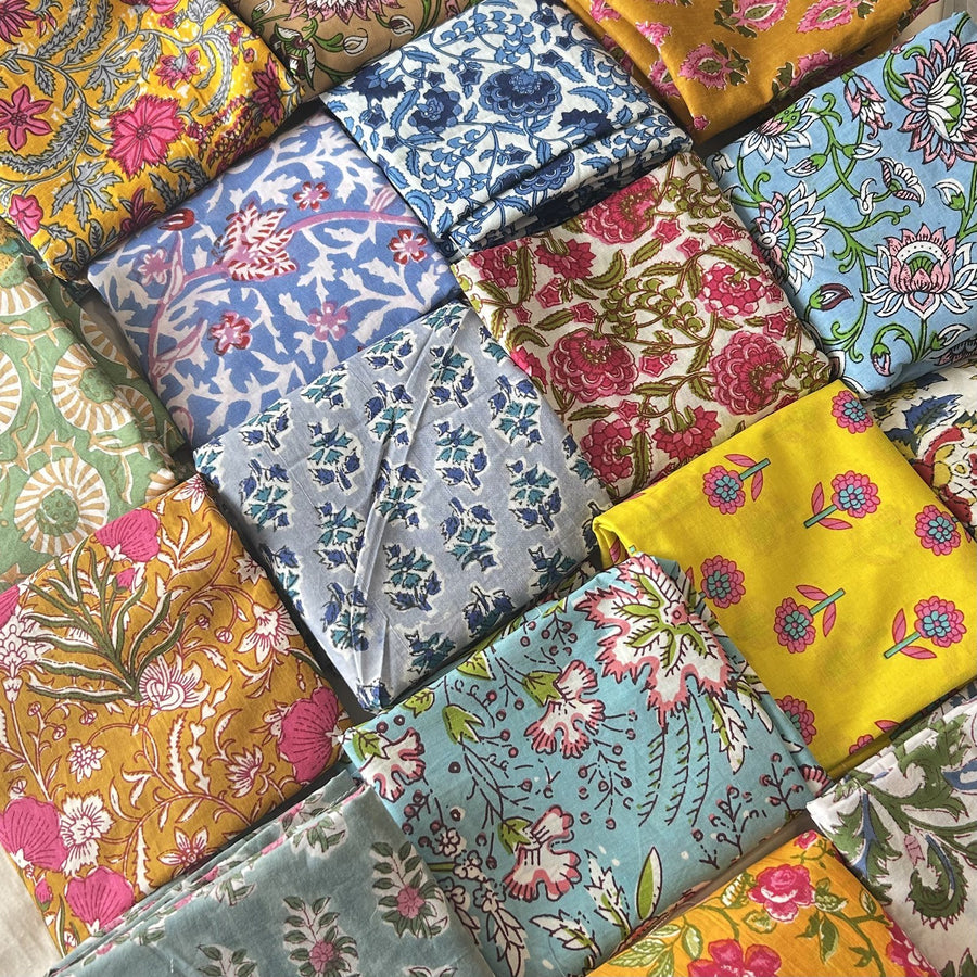 Servilletas de algodón dobladas con estampados florales en amarillo, azul, rosa y verde